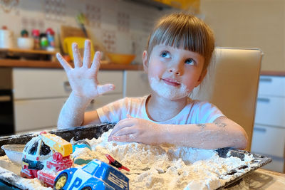 Cute girl plating with toys and flour at home