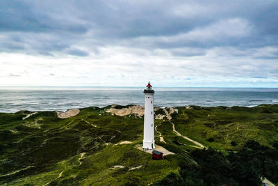 Lighthouse by sea against sky