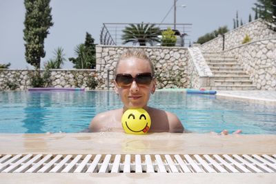 Portrait of mid adult woman wearing sunglasses standing in swimming pool