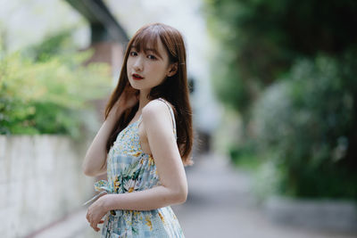 Portrait of young woman standing against trees