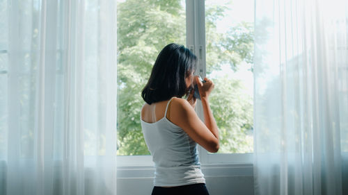 Woman standing by window at home