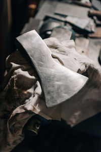 From above of steel axe with sharp blade at workplace iron hatchet on table in workshop