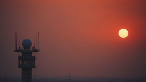 Communications tower against orange sky