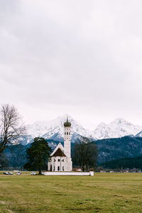 Church on field by building against sky