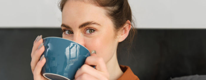 Close-up of young woman drinking coffee at home