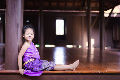 Portrait of smiling girl sitting on wooden floor