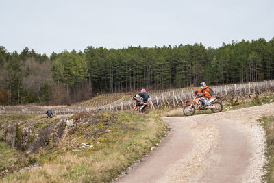 Motocross riders riding motorcycles on dirt road