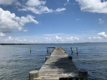 Wooden pier over sea against sky