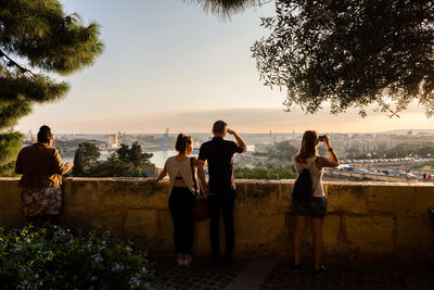 Rear view of tourists by retaining wall at observation point