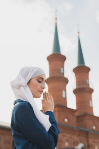 Portrait of young woman against building