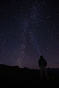 Rear view of man standing against sky at night