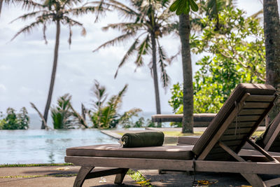 Empty chairs and table by swimming pool against trees