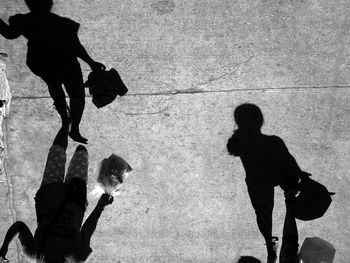 Directly above view of women walking with shadow on footpath