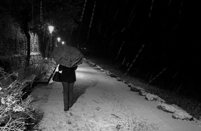 Rear view of woman walking on snow covered road