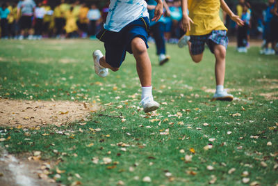 Low section of boys running on grassy field