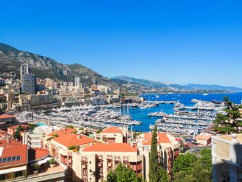 High angle view of townscape by sea against clear blue sky
