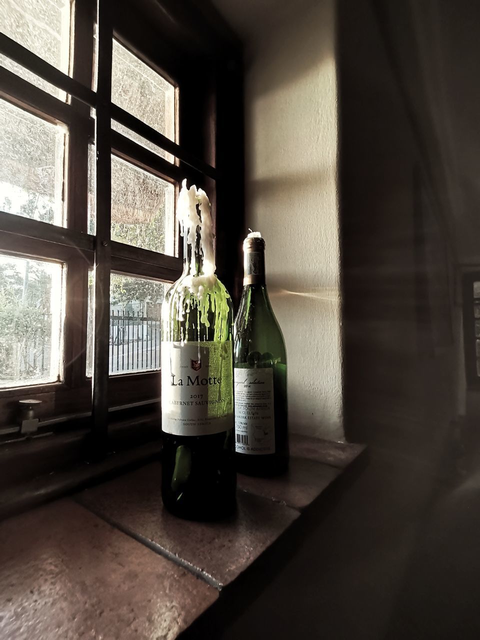 GLASS OF BOTTLES ON WINDOW SILL