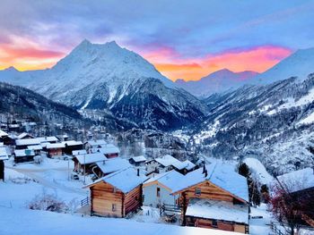 Houses on snow covered mountain against sky