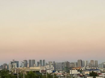 Buildings in city against clear sky during sunset