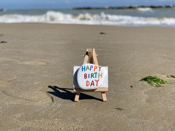 Creative happy birthday text on a colored stone with beach background