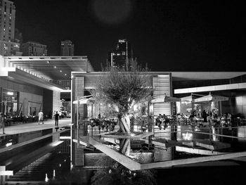 Illuminated restaurant by buildings against sky at night