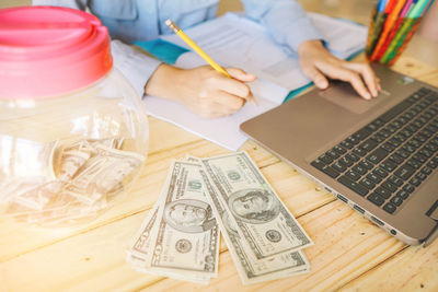 High angle view of businessman working with money and laptop on table