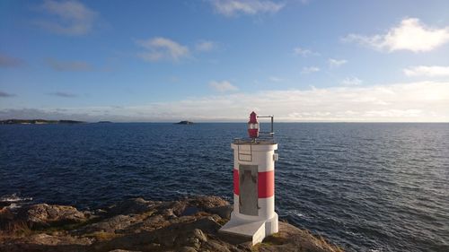 Lighthouse by sea against sky