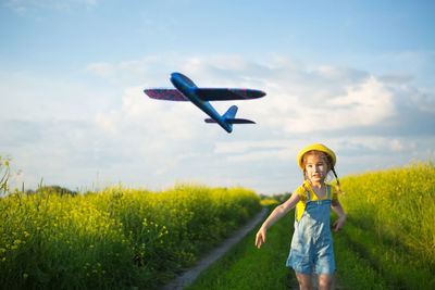 Full length of boy flying over field against sky