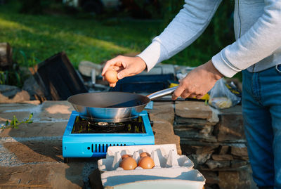 Midsection of man preparing food on camping stove