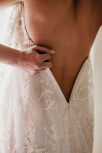 Cropped hands of woman assisting bride while getting dressed