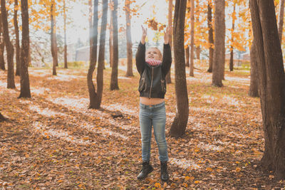 Full length of man standing by tree in forest during autumn