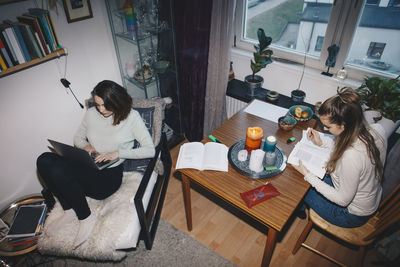 High angle view of young female roommate studying in college dorm room