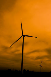 Low angle view of wind turbine against orange sky