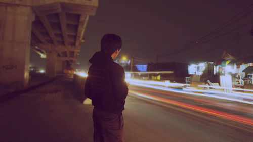 Man standing in front of illuminated light at night