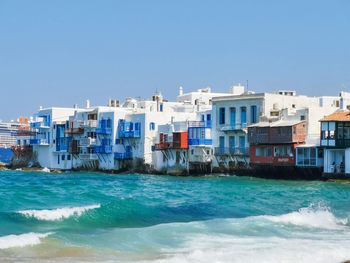 Greek houses by sea against clear blue sky