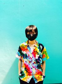 Portrait of woman wearing pollution mask while standing against wall