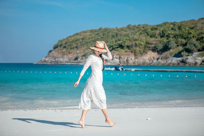 Woman standing on beach against sea against sky