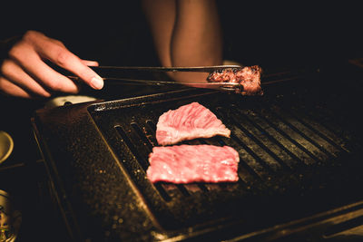 Cropped hand roasting food on barbecue grill