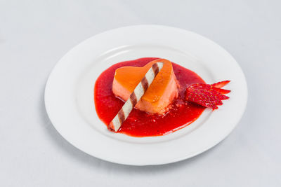 Close-up of strawberry cake on plate against white background