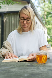 Woman reading book while sitting outdoors