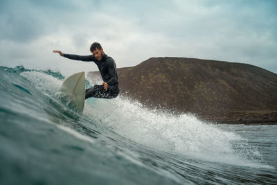 Rear view of man surfing in sea against sky