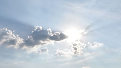 Low angle view of sunlight streaming through clouds
