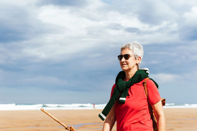 Portrait of mature man wearing sunglasses at beach against sky