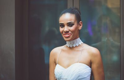 Portrait of smiling young woman standing window