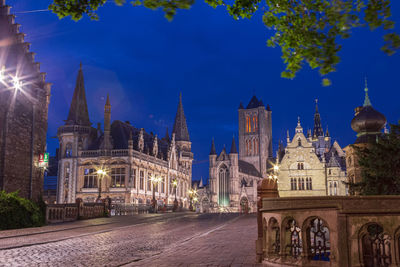 Illuminated buildings against blue sky at night