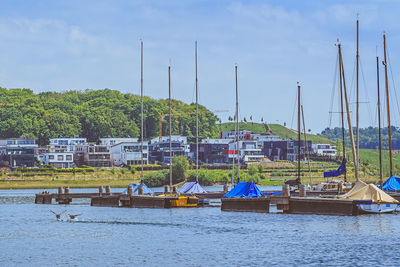 Boats moored at harbor against sky