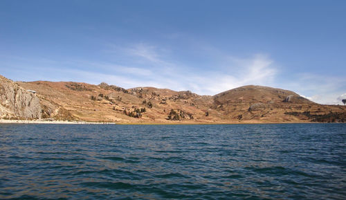 Scenic view of sea and mountains against blue sky