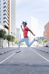 Excited ethnic man jumping on city street