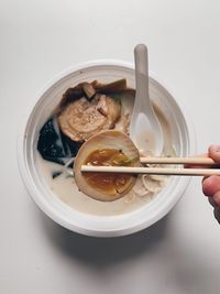 Close-up of hand holding noodles in bowl