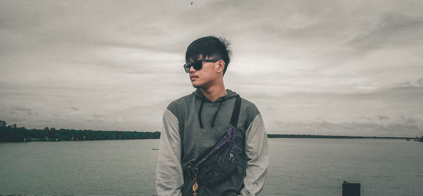 Young man looking at sea against sky